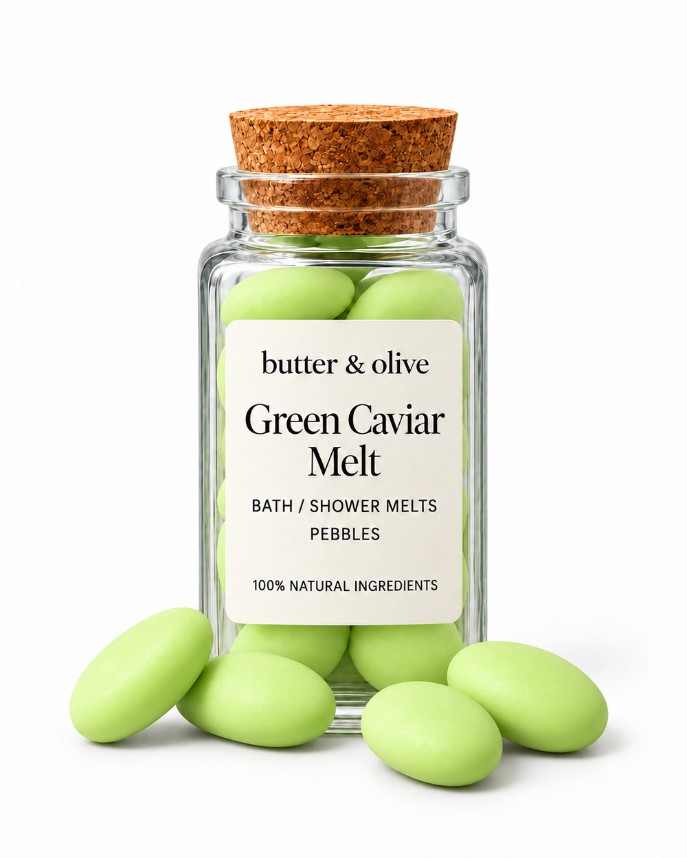 Green Caviar bath and shower melts with four loose pebbles in front of a matching square glass jar